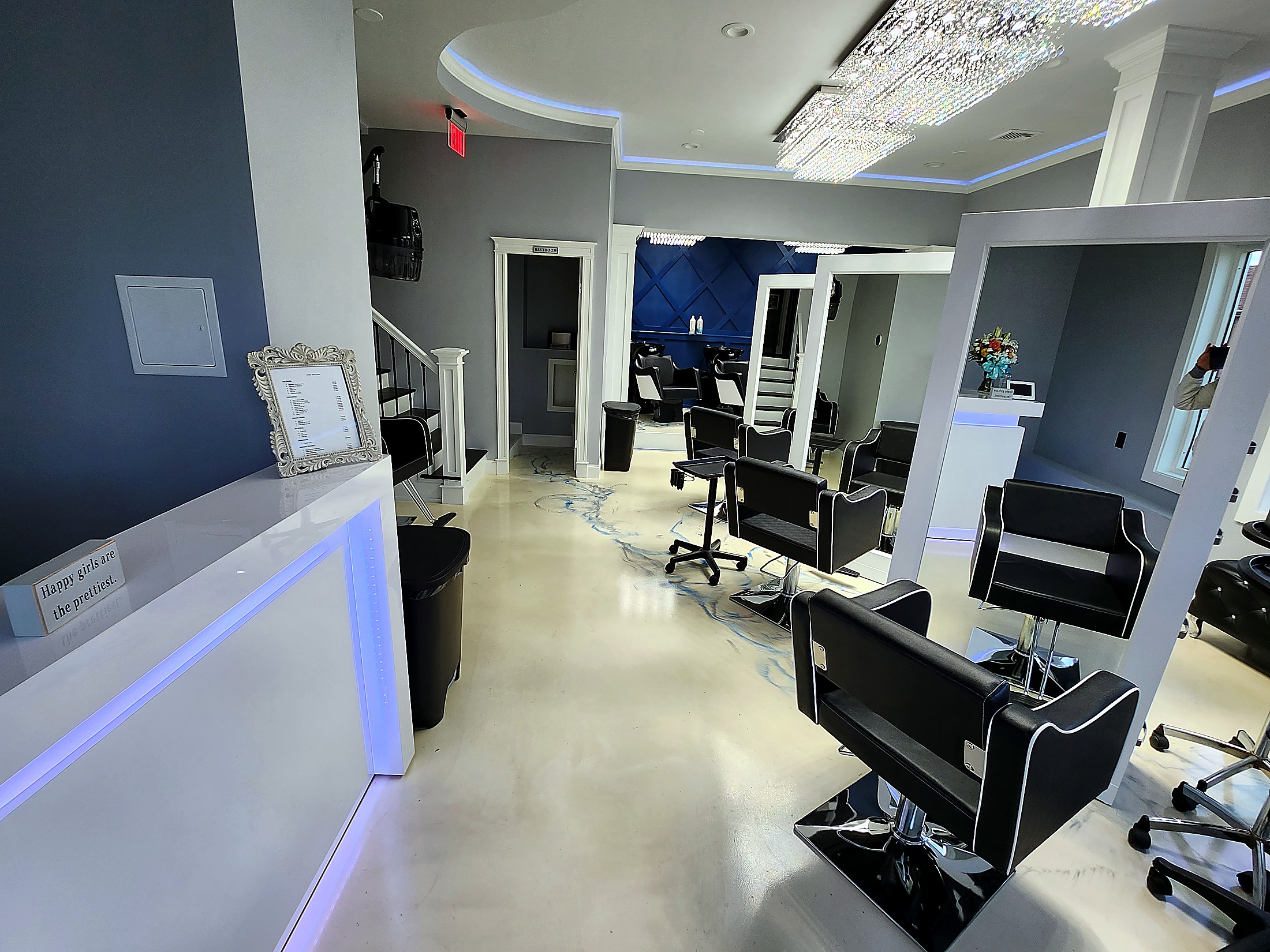 A Hair Story Salon interior view with reception desk, styling stations, crystal chandelier, and the navy accent wall in Fall River MA